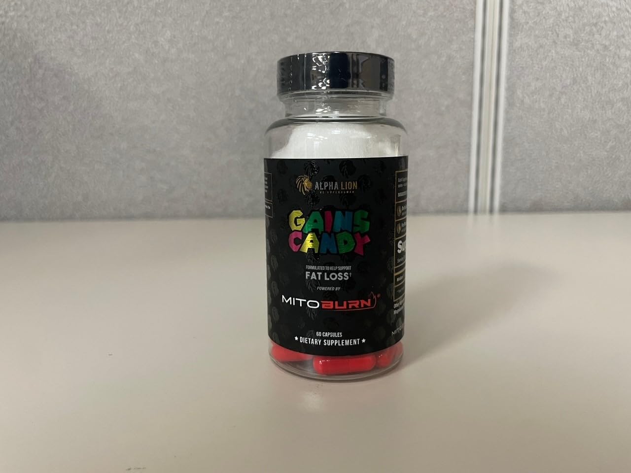 ALPHA LION Gains Candy MitoBurn Fat Burner Capsules displayed with fitness accessories