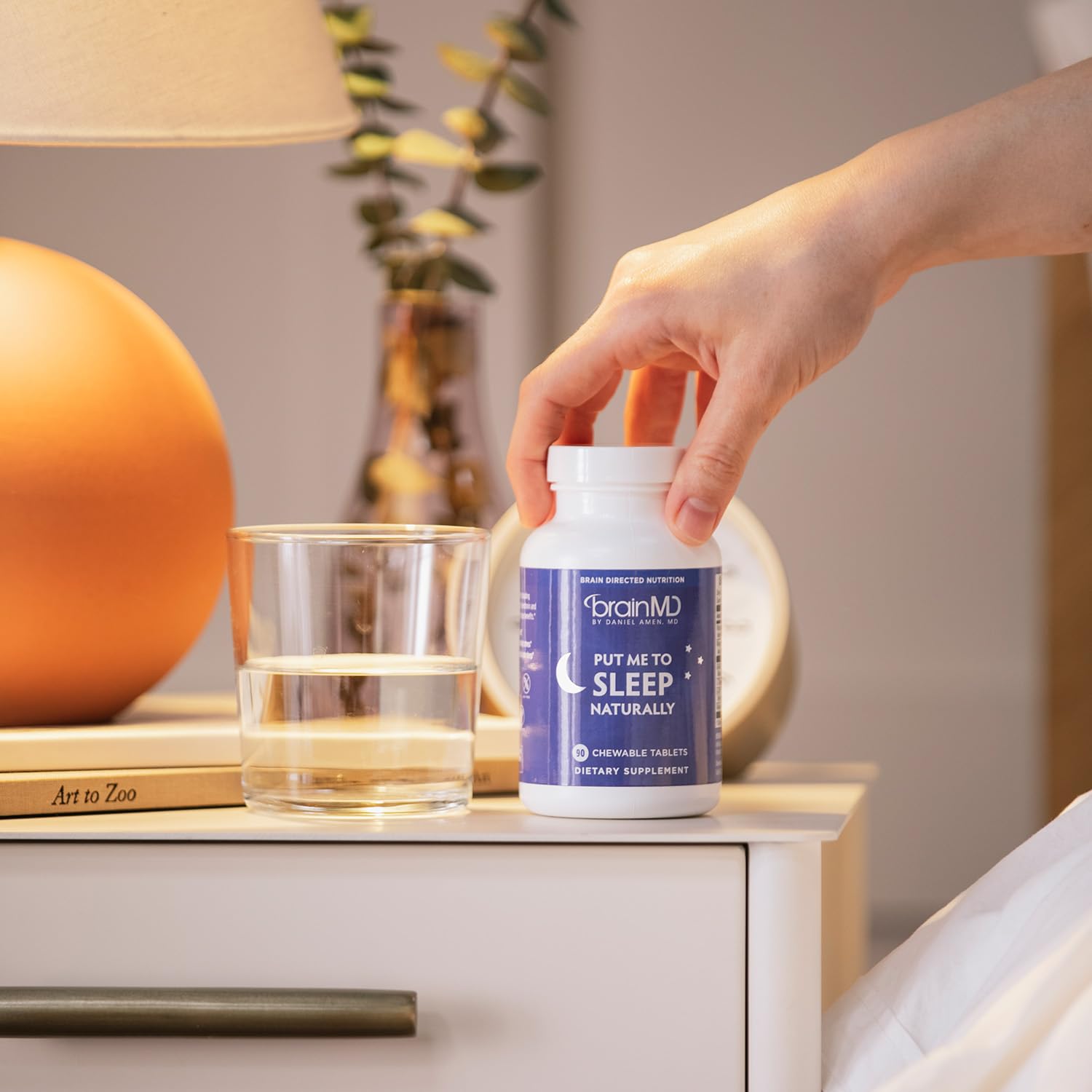 BrainMD Put Me to Sleep Naturally product with a glass of water