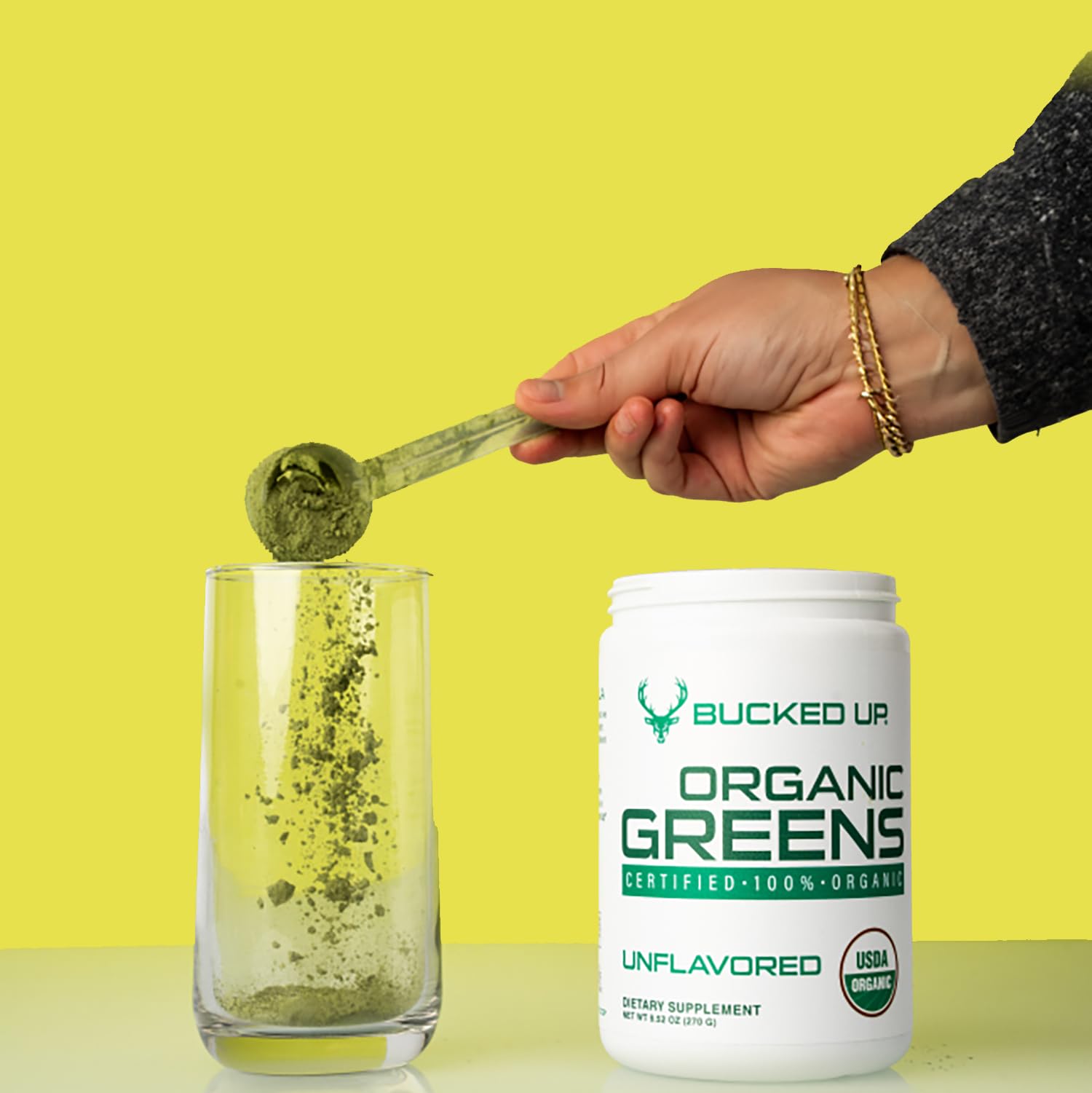 Bucked Up Organic Greens 327g with a smoothie on a kitchen counter