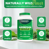 Greens+ Veggie Capsules on a wooden table with a glass of water