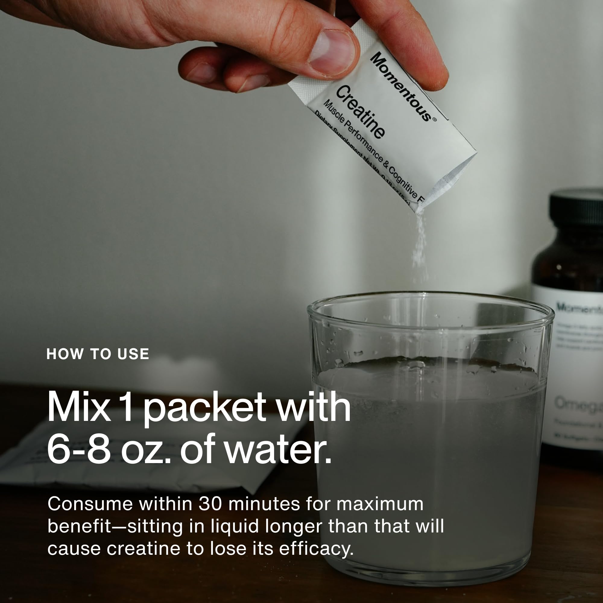 Momentous Creatine Powder 75g on a gym bench with weights