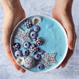 Spoon of blue spirulina powder next to fresh ingredients