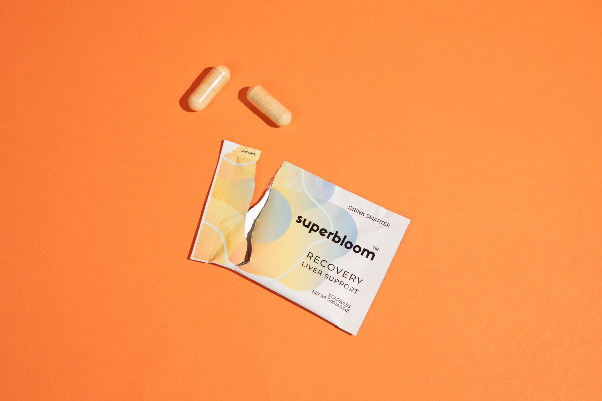 superbloom Milk Thistle supplement on a table with a glass of water