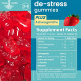 True Roots Stress Gummies on a wooden table with fresh strawberries