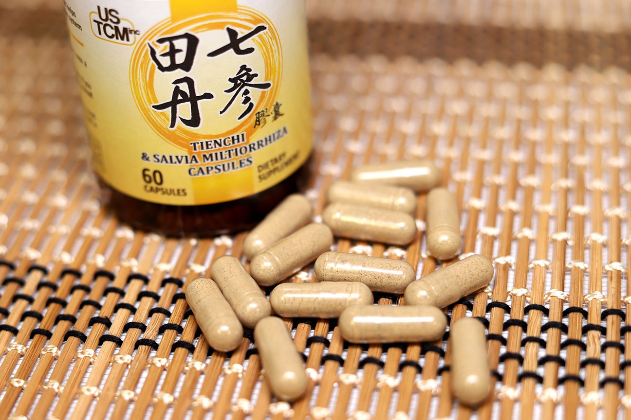 USTCM Blended Vitamin & Mineral Supplement capsules on a wooden surface